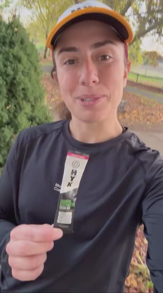 Woman running and drinking HYK electrolytes to rehydrate.